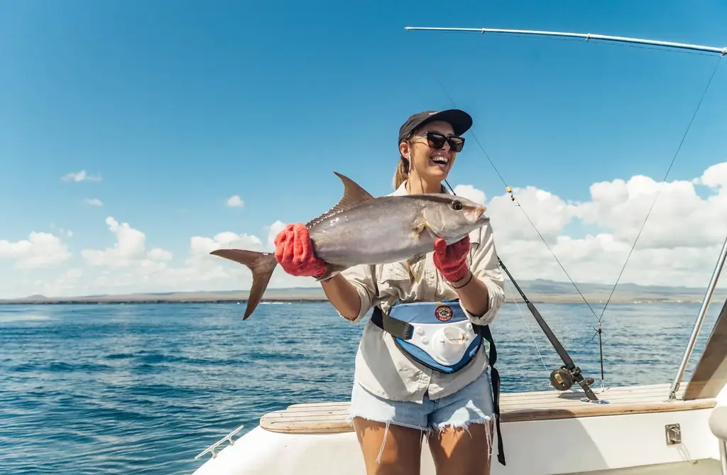 Guest holding a catch aboard a fishing excursion